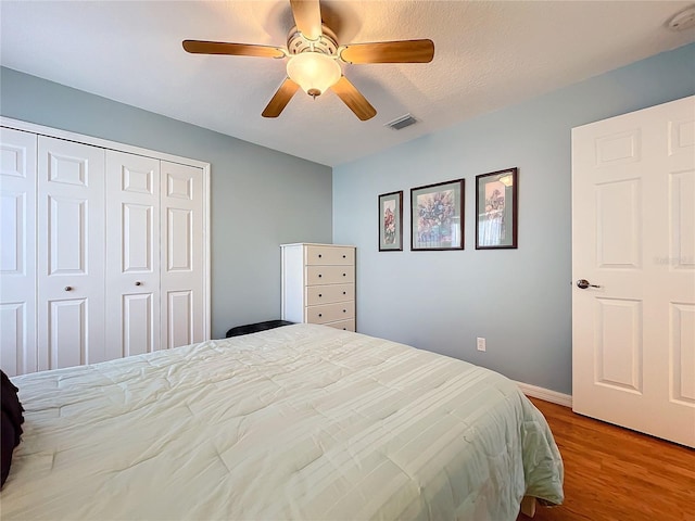 bedroom featuring ceiling fan, a closet, a textured ceiling, and light hardwood / wood-style flooring