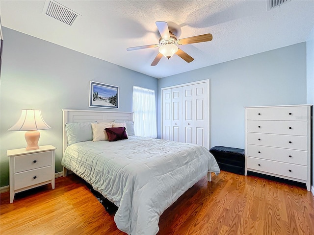 bedroom featuring hardwood / wood-style floors, a textured ceiling, a closet, and ceiling fan