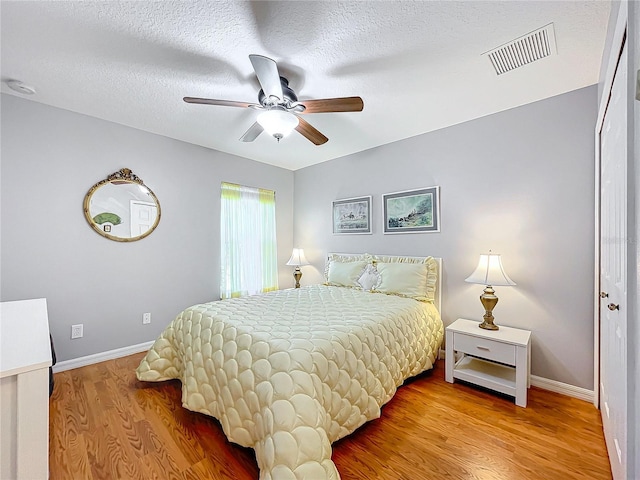 bedroom featuring ceiling fan, wood-type flooring, and a textured ceiling