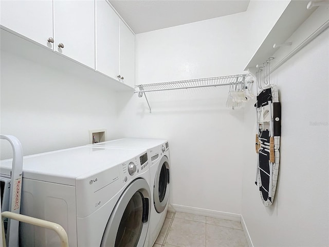 laundry area with washer and clothes dryer, cabinets, and light tile patterned floors