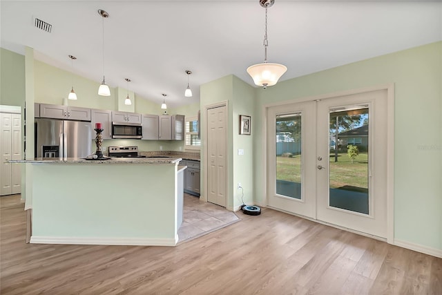 kitchen featuring hanging light fixtures, light hardwood / wood-style floors, gray cabinets, a kitchen island, and appliances with stainless steel finishes