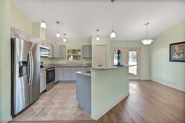 kitchen with pendant lighting, a center island, stainless steel appliances, and light hardwood / wood-style flooring