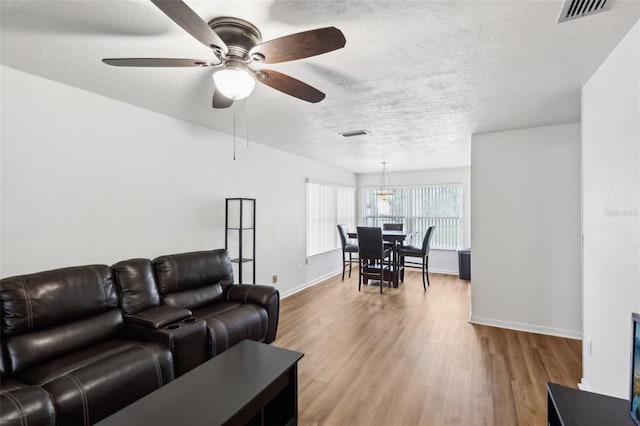 living room with ceiling fan, light hardwood / wood-style floors, and a textured ceiling