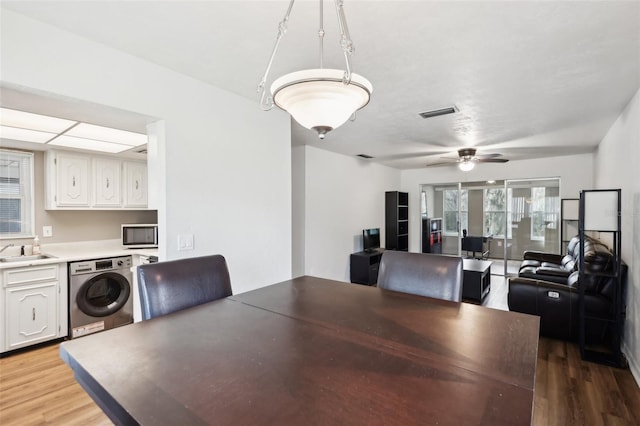 dining space featuring sink, hardwood / wood-style floors, ceiling fan, and washer / dryer