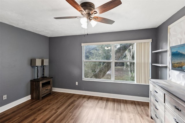 unfurnished living room featuring ceiling fan and dark wood-type flooring