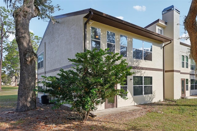 view of side of property featuring a yard and central AC