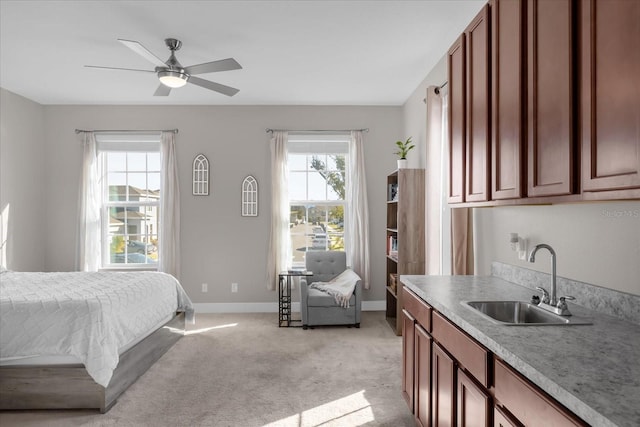 carpeted bedroom with ceiling fan, multiple windows, and sink