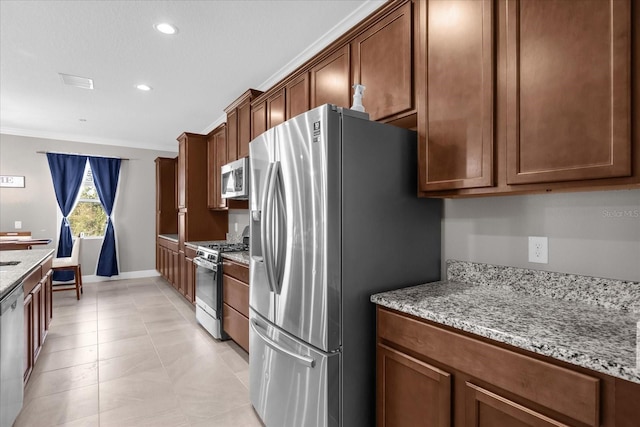 kitchen featuring appliances with stainless steel finishes, light stone counters, ornamental molding, and light tile patterned flooring