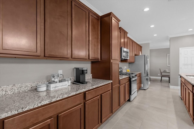 kitchen with light tile patterned flooring, light stone countertops, ornamental molding, and appliances with stainless steel finishes