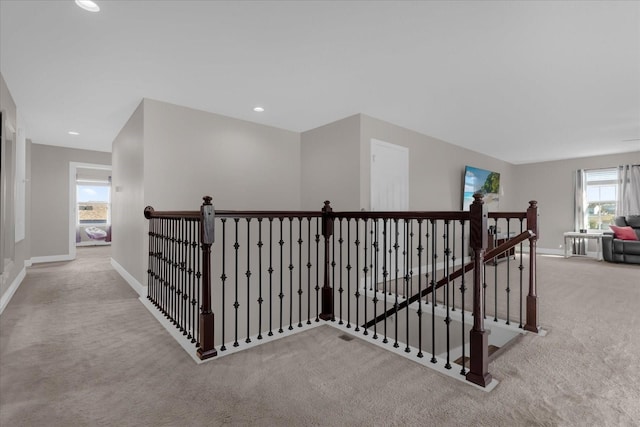 hall featuring light carpet and plenty of natural light