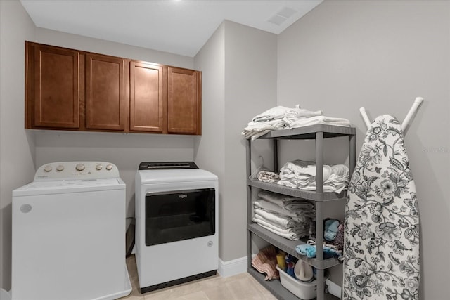 laundry room featuring washer and clothes dryer and cabinets