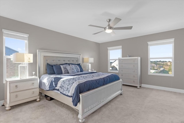 bedroom with ceiling fan, light colored carpet, and multiple windows