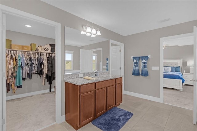 bathroom featuring tile patterned floors, vanity, and ceiling fan with notable chandelier