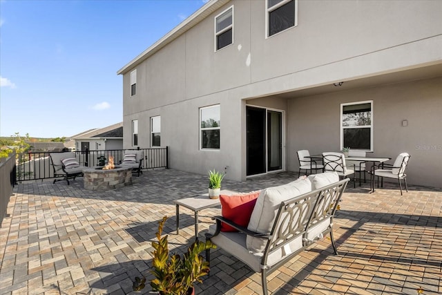 rear view of house with an outdoor living space with a fire pit and a patio area