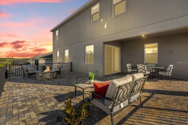 patio terrace at dusk with an outdoor living space with a fire pit