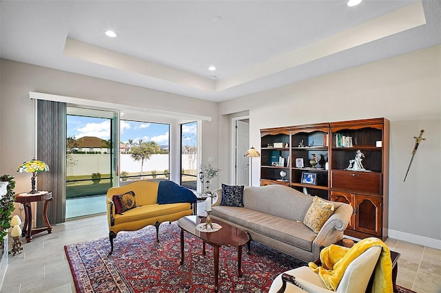 living room with baseboards, a tray ceiling, and recessed lighting