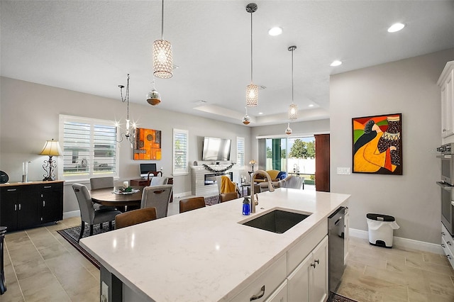 kitchen featuring recessed lighting, a sink, open floor plan, dishwasher, and decorative light fixtures