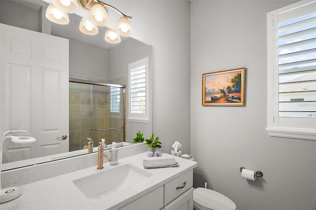 bathroom with toilet, a shower stall, a notable chandelier, and vanity