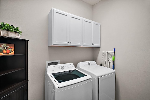 washroom featuring cabinet space and washer and clothes dryer