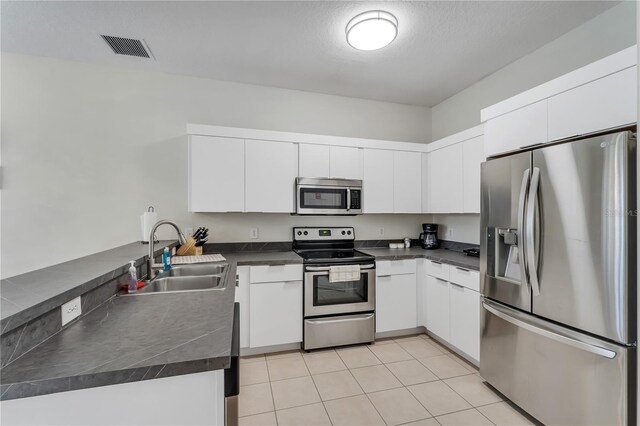 kitchen with kitchen peninsula, sink, white cabinetry, and stainless steel appliances