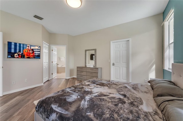 bedroom with hardwood / wood-style flooring and connected bathroom