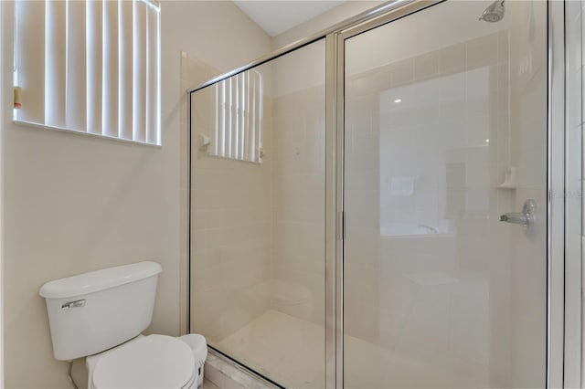 bathroom featuring toilet and a shower with shower door