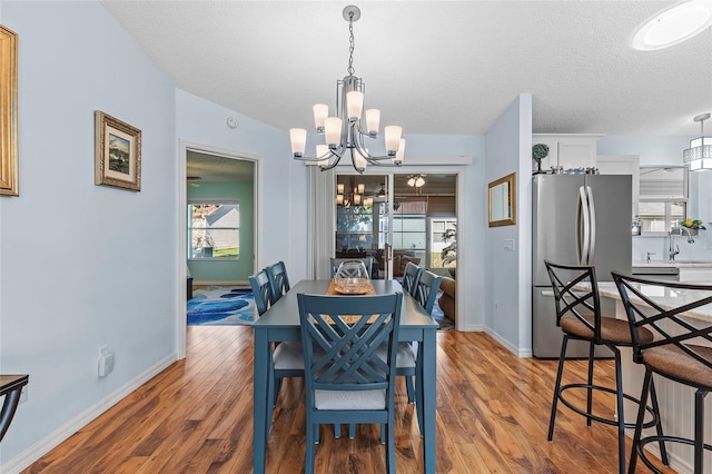 dining space with a wealth of natural light, hardwood / wood-style floors, and an inviting chandelier