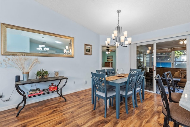 dining space with ceiling fan with notable chandelier, wood-type flooring, lofted ceiling, and a textured ceiling