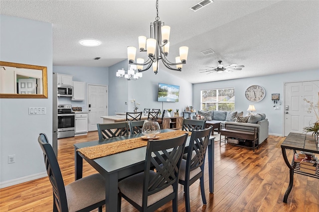 dining room featuring ceiling fan with notable chandelier, lofted ceiling, a textured ceiling, and light hardwood / wood-style flooring