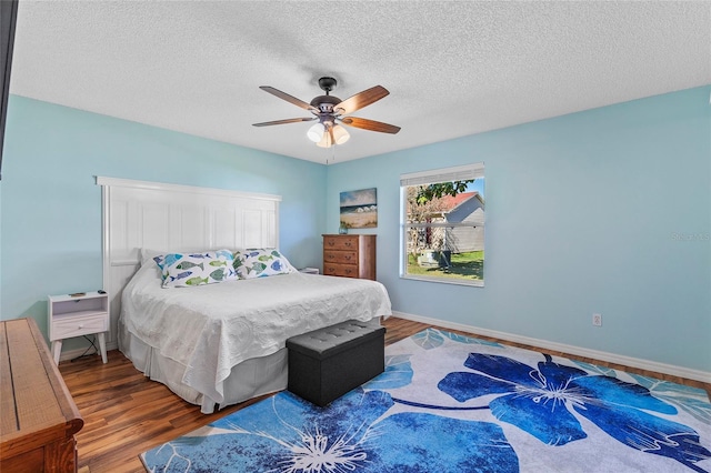 bedroom with a textured ceiling, hardwood / wood-style flooring, and ceiling fan