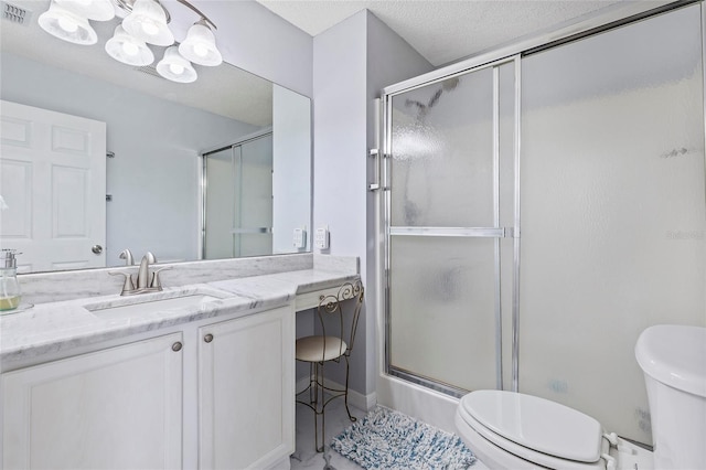 bathroom featuring vanity, toilet, an enclosed shower, and a textured ceiling