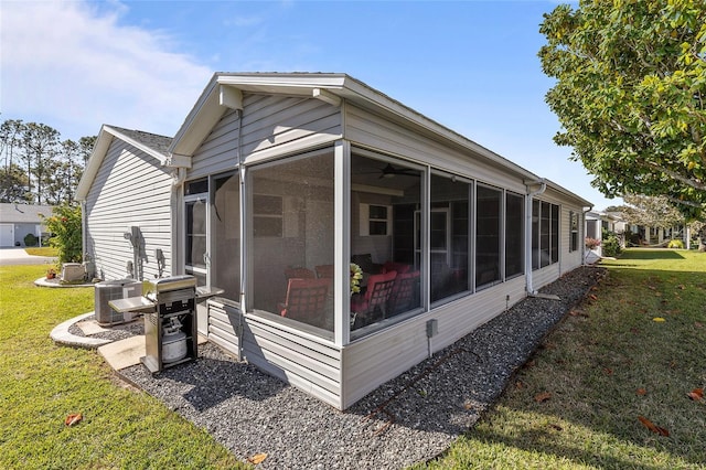 rear view of house featuring a yard, cooling unit, and a sunroom