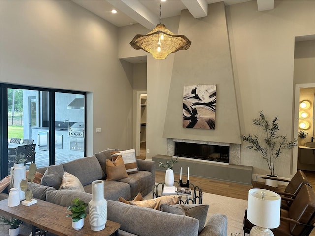 living area featuring beam ceiling, a fireplace, recessed lighting, wood finished floors, and a towering ceiling