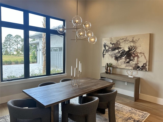 dining area with baseboards, a notable chandelier, plenty of natural light, and wood finished floors