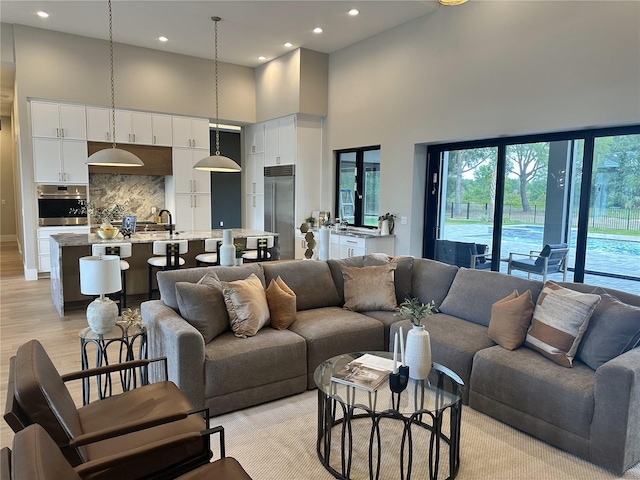 living room with a high ceiling, recessed lighting, and light wood-style flooring