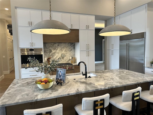 kitchen with a sink, appliances with stainless steel finishes, tasteful backsplash, and white cabinetry