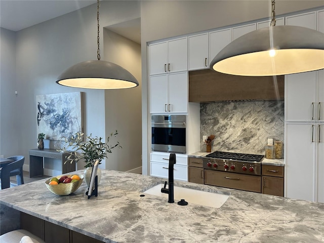 kitchen featuring decorative backsplash, light stone countertops, white cabinetry, a sink, and stainless steel appliances