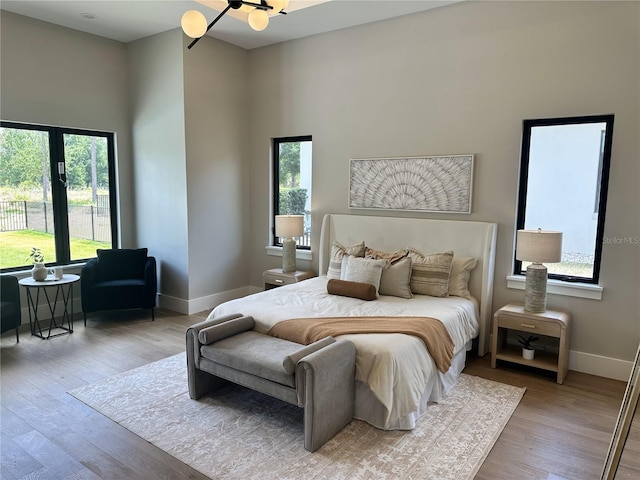 bedroom with baseboards, wood finished floors, and multiple windows