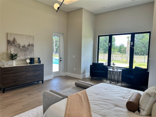 bedroom featuring baseboards, access to outside, multiple windows, and wood finished floors