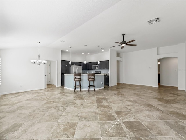 kitchen with ceiling fan with notable chandelier, a kitchen island, a breakfast bar area, and stainless steel appliances