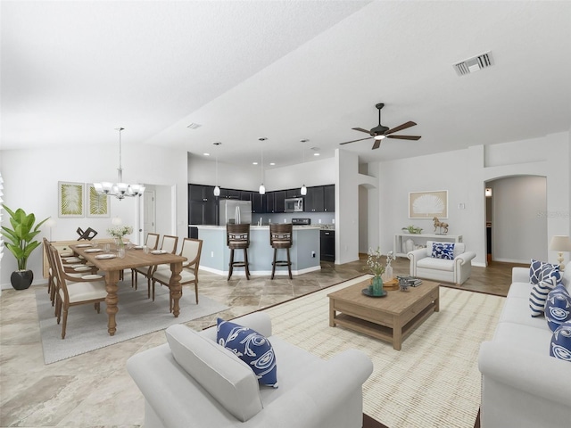 living room with vaulted ceiling and ceiling fan with notable chandelier