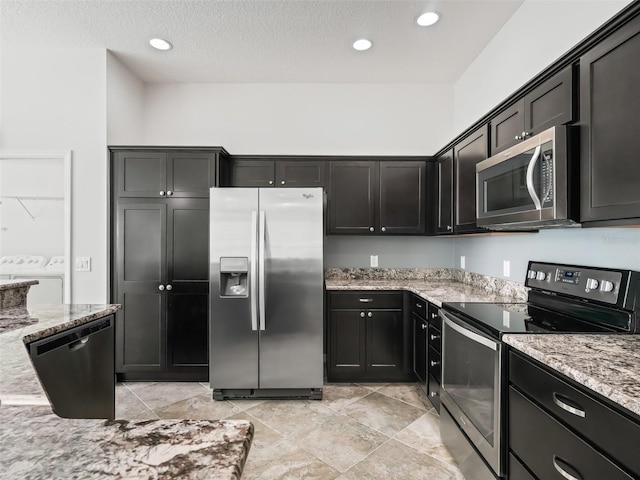 kitchen with light stone countertops, washer and clothes dryer, a textured ceiling, and appliances with stainless steel finishes