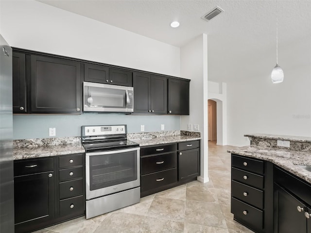 kitchen with light stone countertops, appliances with stainless steel finishes, and pendant lighting