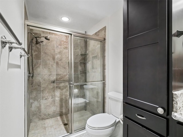 bathroom featuring toilet and a shower with shower door