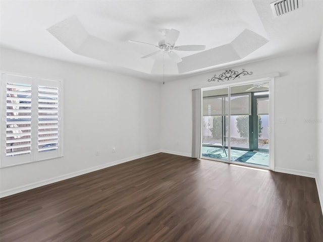 spare room featuring a raised ceiling, ceiling fan, and dark hardwood / wood-style flooring