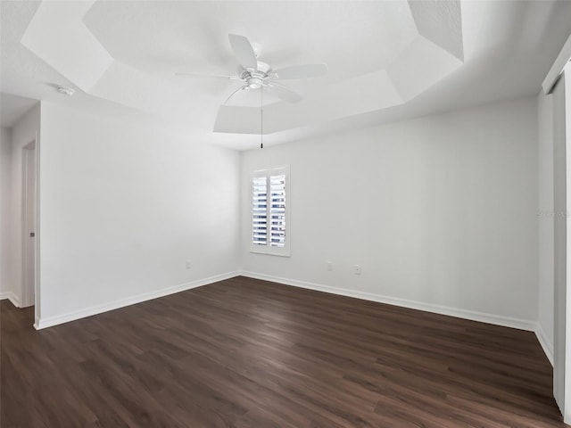 spare room featuring a tray ceiling, ceiling fan, and dark hardwood / wood-style flooring