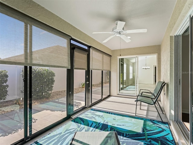 unfurnished sunroom with ceiling fan with notable chandelier