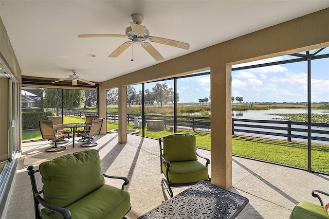 sunroom / solarium featuring ceiling fan and a water view