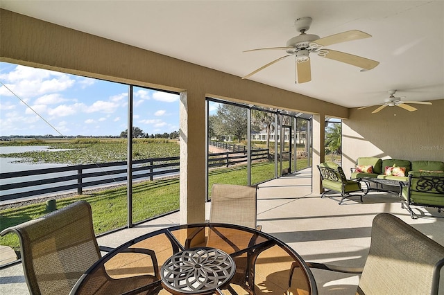 sunroom / solarium with ceiling fan, a water view, and a rural view