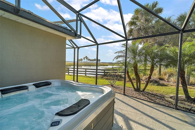 view of patio / terrace featuring a hot tub, a water view, and glass enclosure